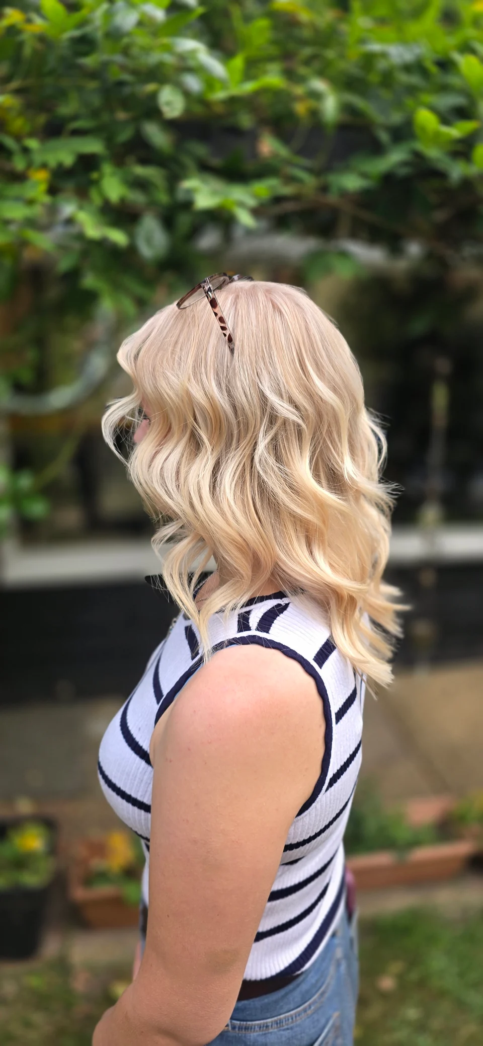 Blonde hair with soft waves and a darker root, viewed from the side